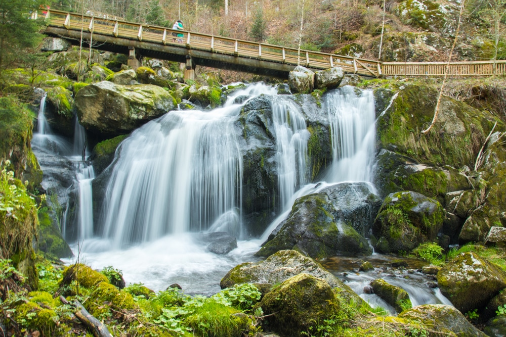 de watervallen van Triberg met op de achtergrond een weg waar twee mensen elkaar knuffelen