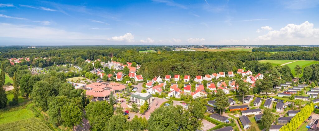 Luchtfoto van Roompot Resort Arcen. Je ziet huisjes, stacaravans en het hoofdgebouw omringd door bossen en velden.