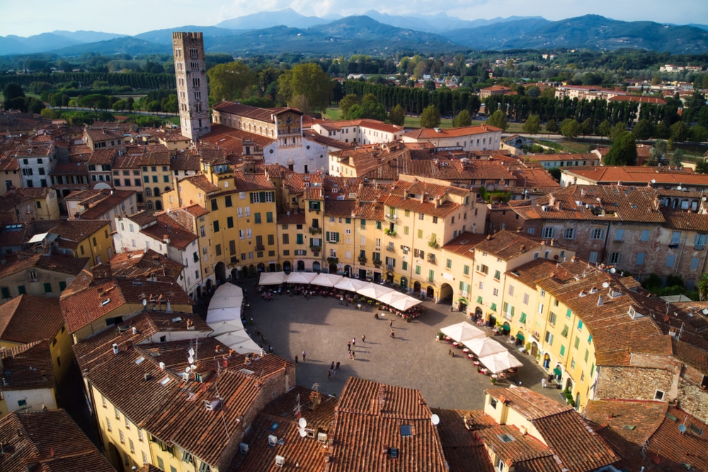 luchtfoto van het Piazza dell’Anfiteatro in Lucca, een ovaal plein met aan de zijkant terrassen. Het wordt omringd door hoge gebouwen