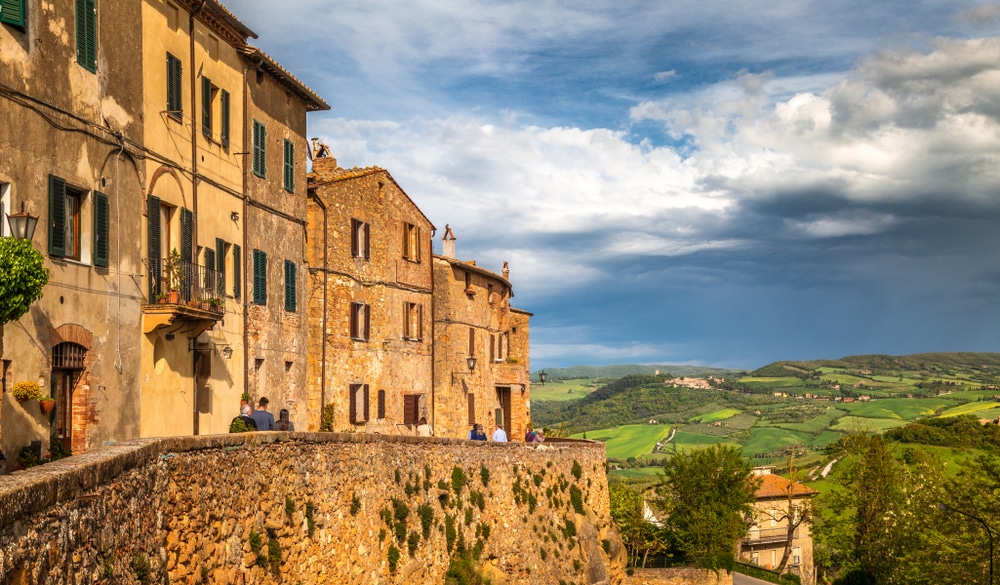 oranje, stenen huizen op een heuvel in het Toscaanse dorpje Pienza. In de verte kijk je op een groen heuvellandschap