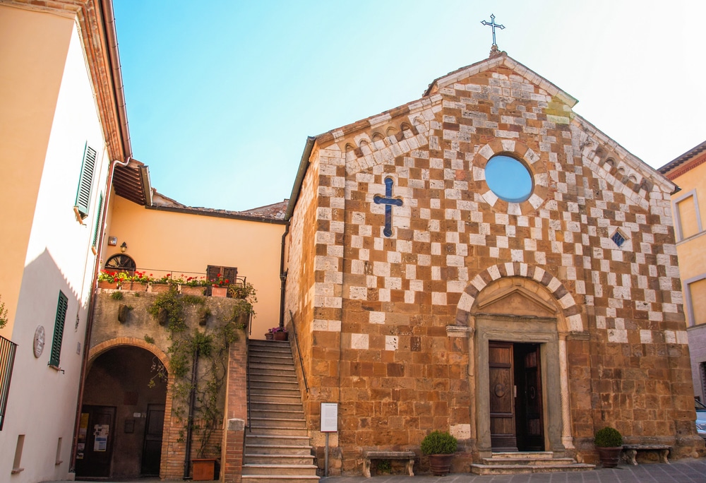 foto van het kleine kerkje in het Toscaanse dorpje Trequanda met wit en beige geblokte stenen