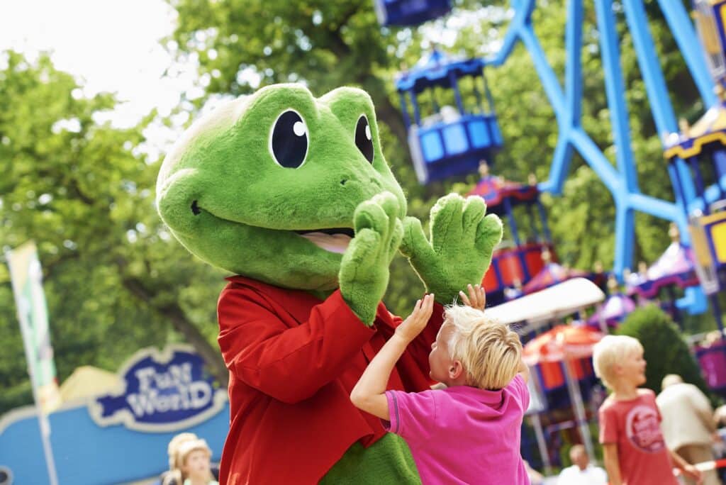 foto van een jongetje in een roze polo die de mascotte van Duinrell een high five geeft