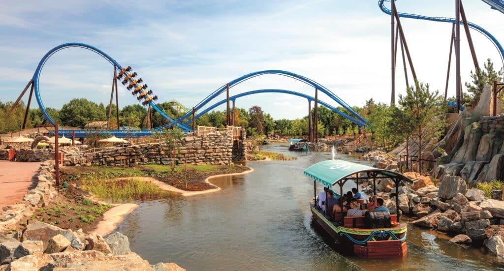 bootje met mensen dat over het water en tussen de achtbanen doorvaart in Attractiepark Toverland