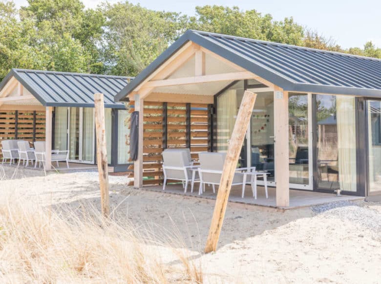 twee houten chalets met veranda met loungestoelen op Roompot Vakantiepark Ameland