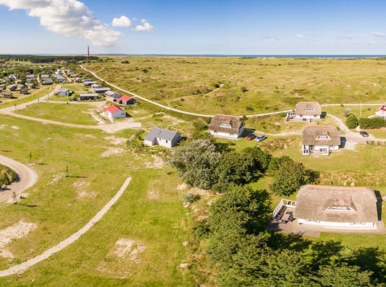 Vakantiehuizen op Vakantiepark Boomhiemke op het Waddeneiland Ameland gezien van bovenaf. In de verte zie je de zee.