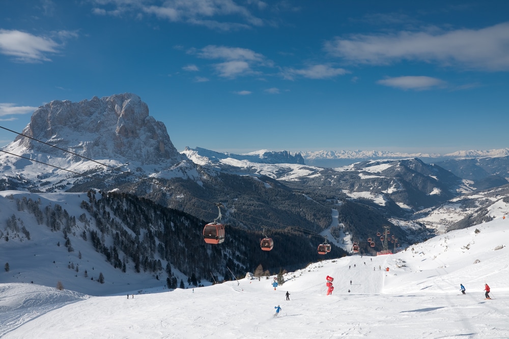 skiërs en skilift in het skigebied Val Gardena in Italië en besneeuwde bergen op de achtergrond