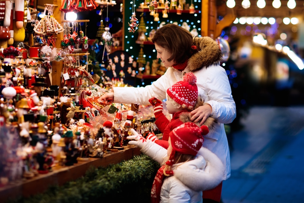 moeder met kinderen bij kerstkraampje op kersmarkt