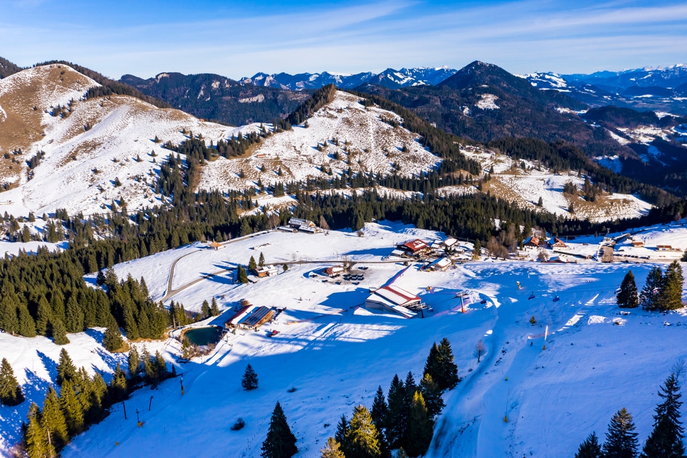 skigebied Bayrischzell met pistes, skistations, liften, en rondom bomen en gedeeltelijk besneeuwde bergen
