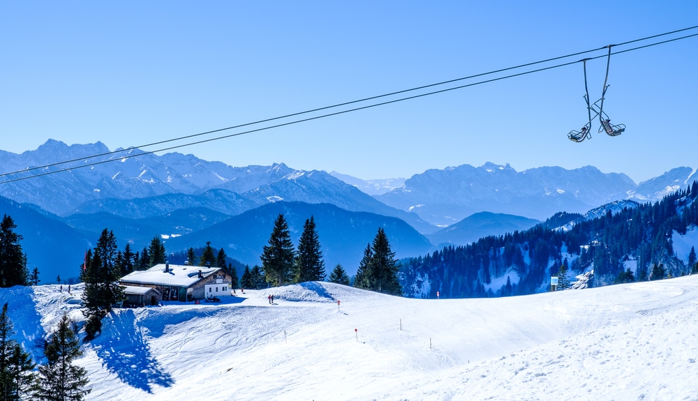 skipiste met skistation en stoeltjeslift en in de verte diverse bergen in het wintersportgebied Brauneck in Duitsland