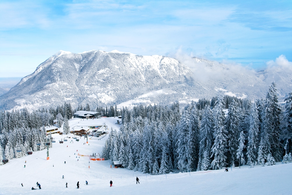 skipiste met skiërs en skistations, bomen aan de zijkant en bergen op de achtergrond in het skigebied Garmisch-Partenkirchen in Duitsland