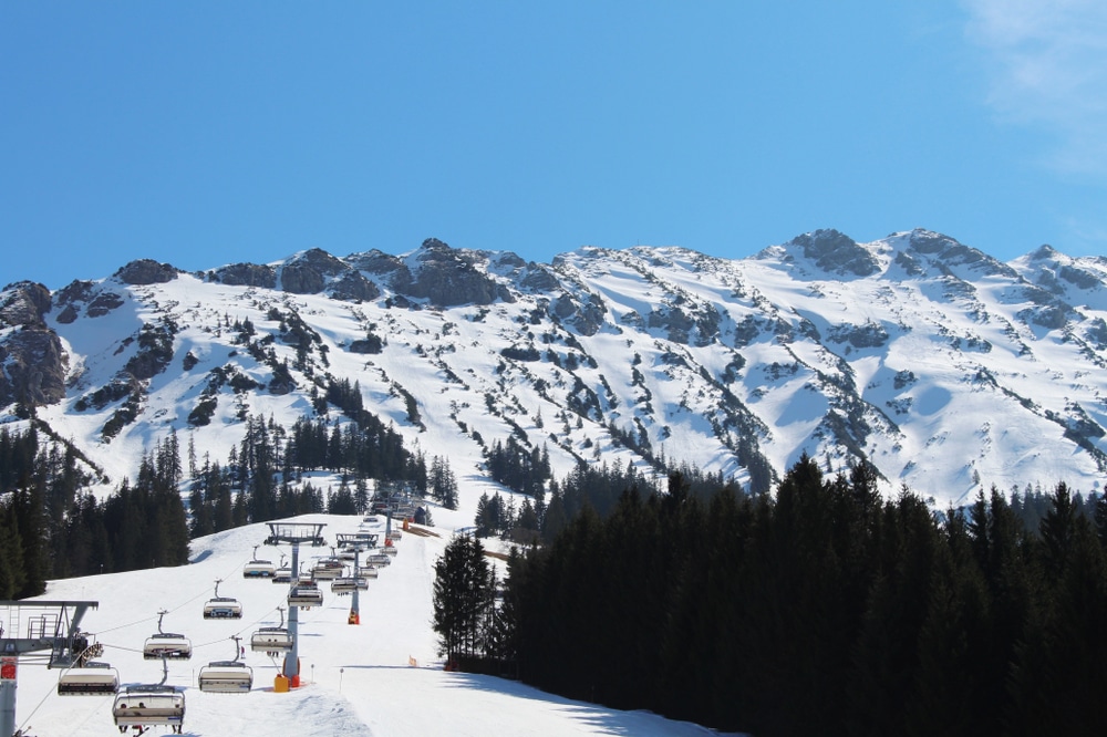 skipiste met daarboven een draaiende stoeltjeslift met kap en op de achtergrond bergen in het wintersportgebied Oberjoch-Unterjoch in Duitsland