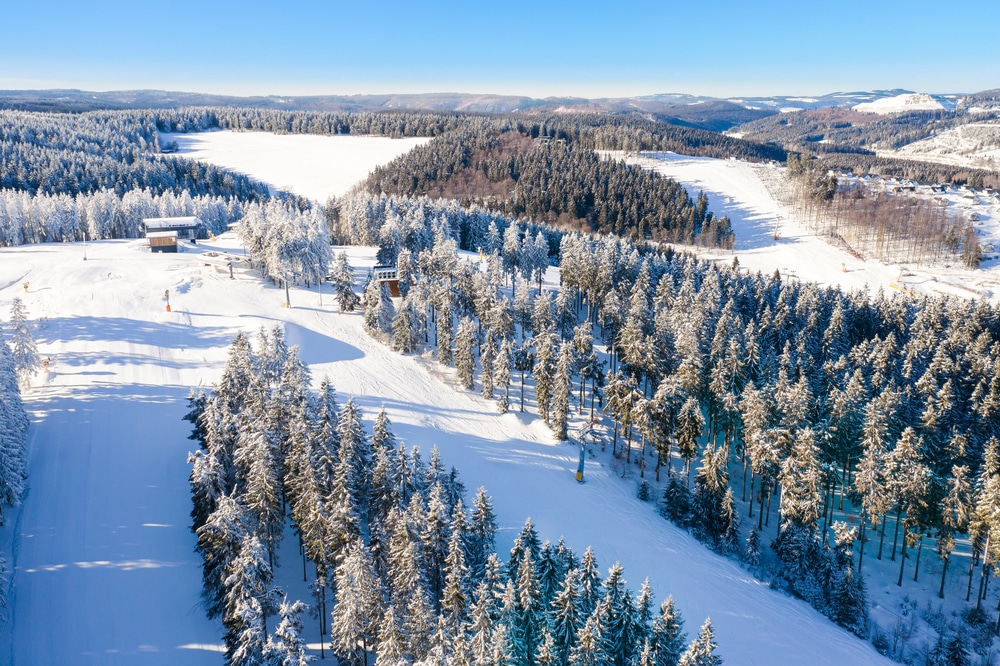 redelijk vlakke en lege skipistes met daar omheen besneeuwde bomen in het skigebied Skiliftkarussell Winterberg in Duitsland