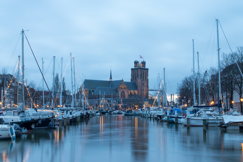 De Oude Haven in Dordrecht met verlichte bootjes in de winter en de Grote Kerk op de achtergrond