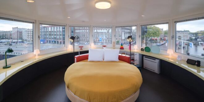 rond tweepersoonsbed in een ronde suite met panoramisch uitzicht op de straten en het water in Amsterdam