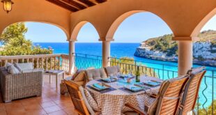 terras van een vakantiehuis met een gedekte tafel en een loungehoek en uitzicht op een azuurblauwe baai in Mallorca